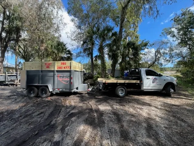 Truck and trailer under trees.